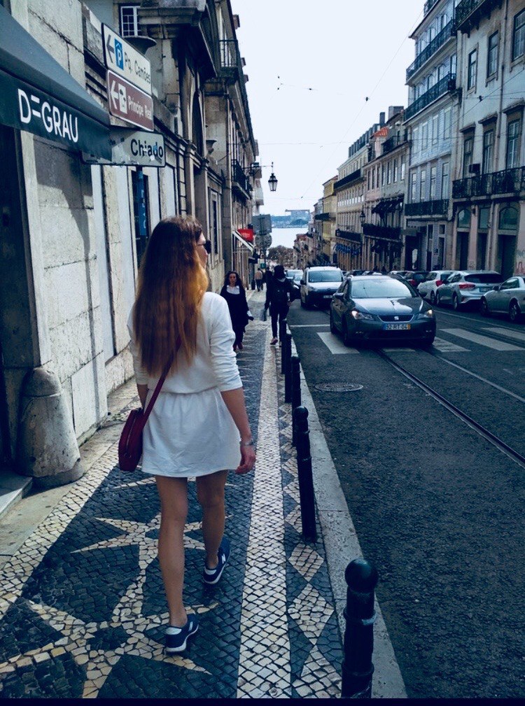 Walking down a traditional cobblestone street with tram tracks in the Chiado neighborhood, Lisbon