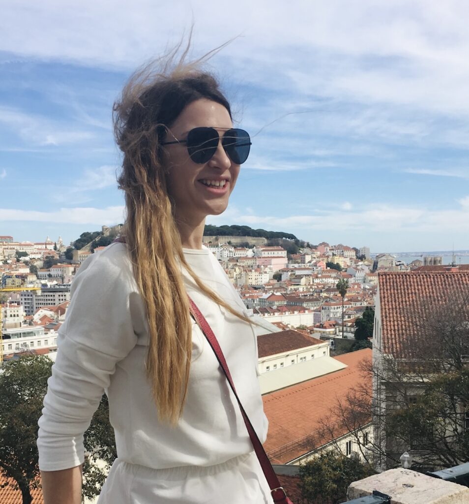Woman in sunglasses smiling with a panoramic view of Lisbon behind her
