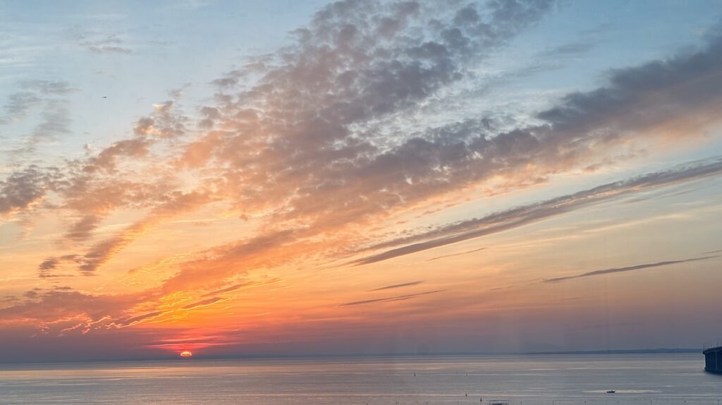 Sunrise over the water in Lisbon with soft clouds and warm early morning light