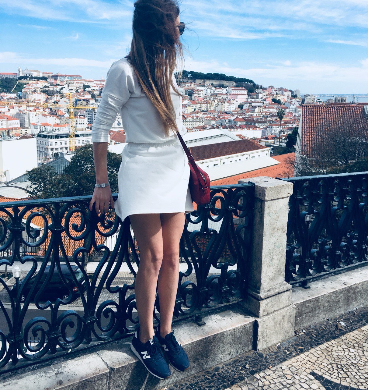 Woman looking at the panoramic view of Lisbon's traditional red roofs and river on a sunny day