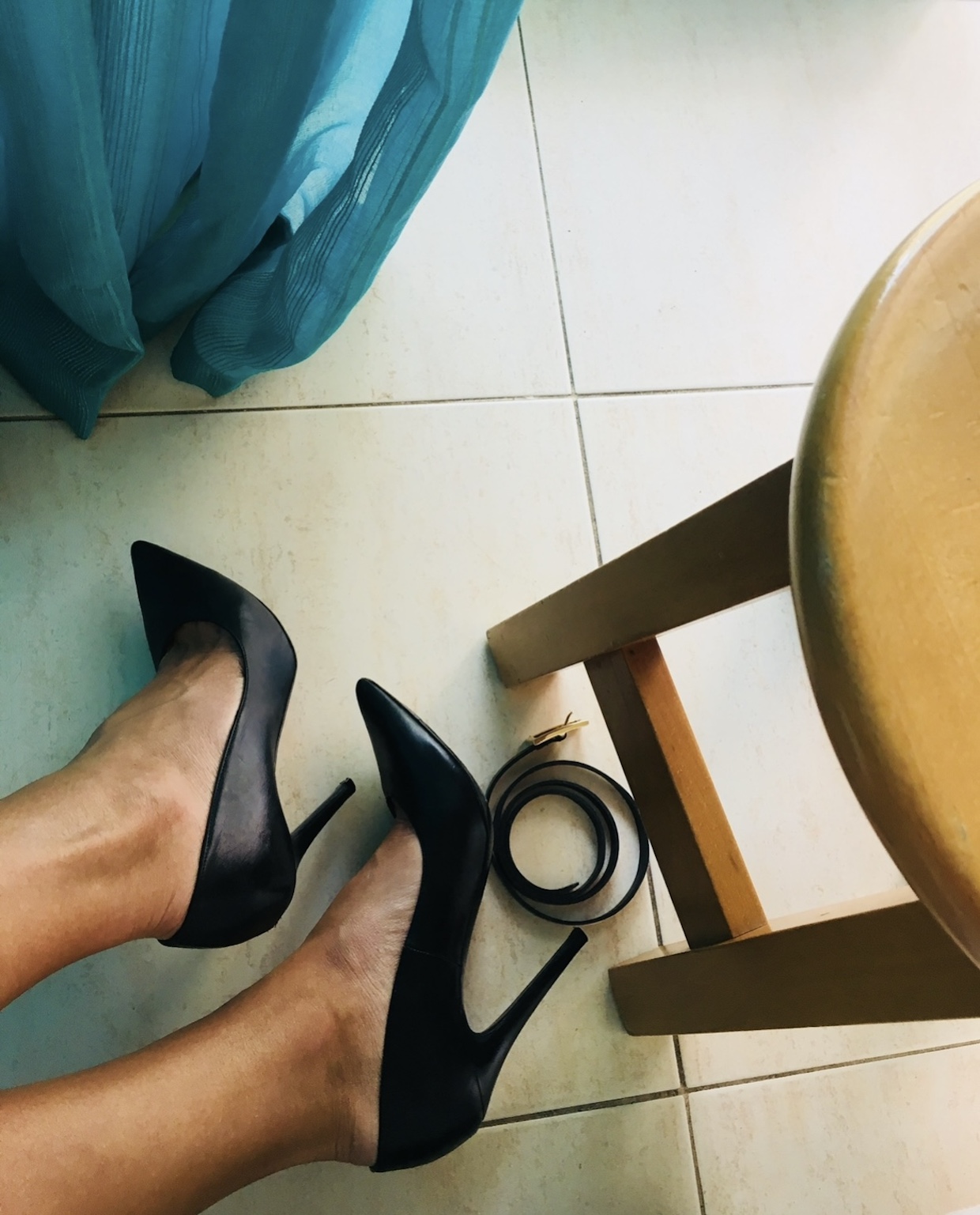 Black heels and a belt on the floor before an evening out in Lisbon