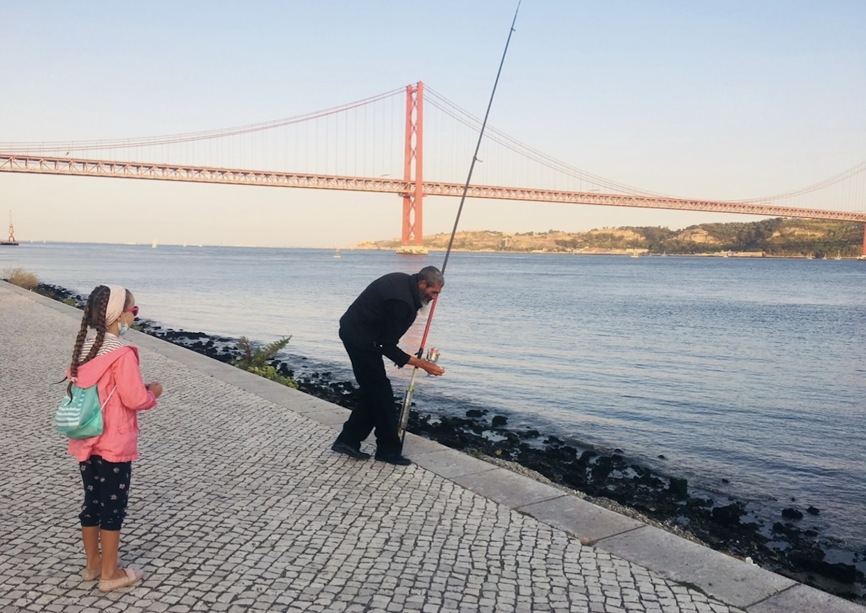 Fisherman by the Tagus River in Belém, Lisbon, with the 25 de Abril Bridge in the background
