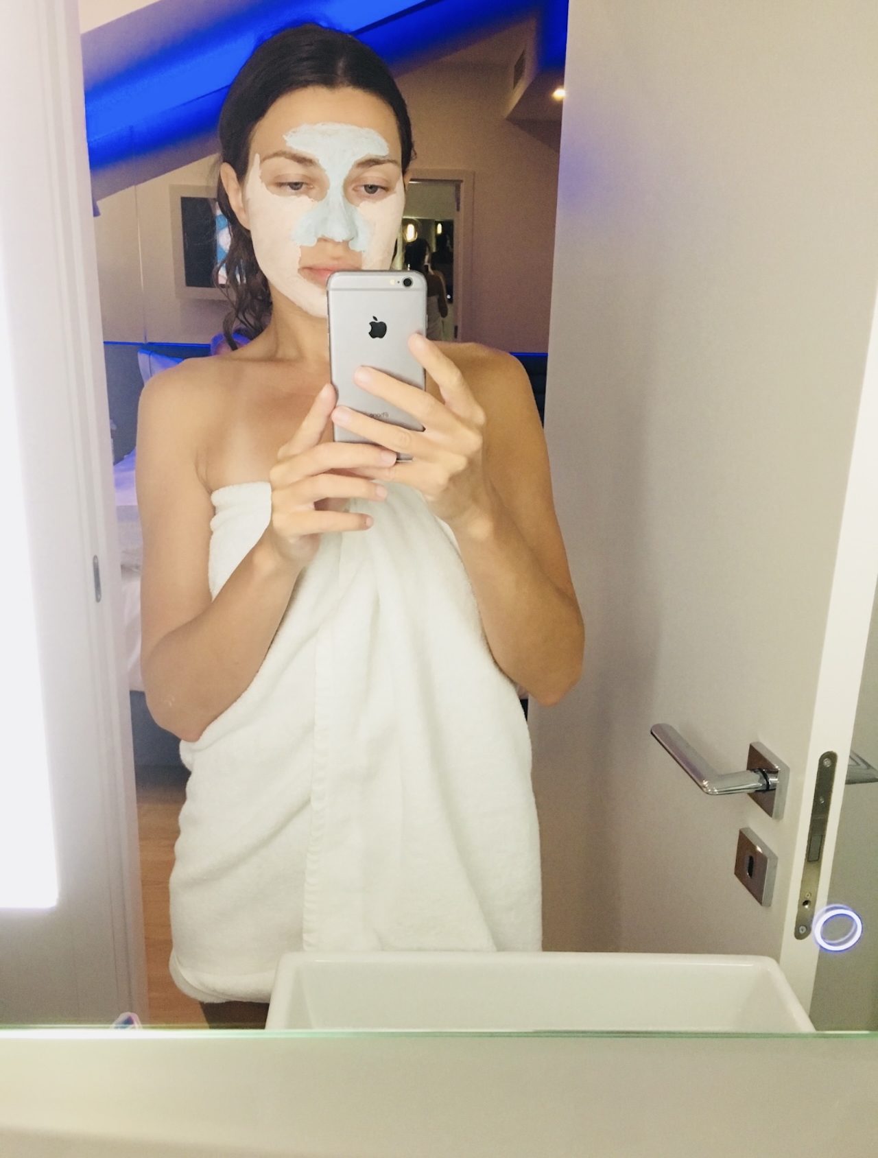 Woman in a towel applying a face mask during a quiet skin reset ritual.