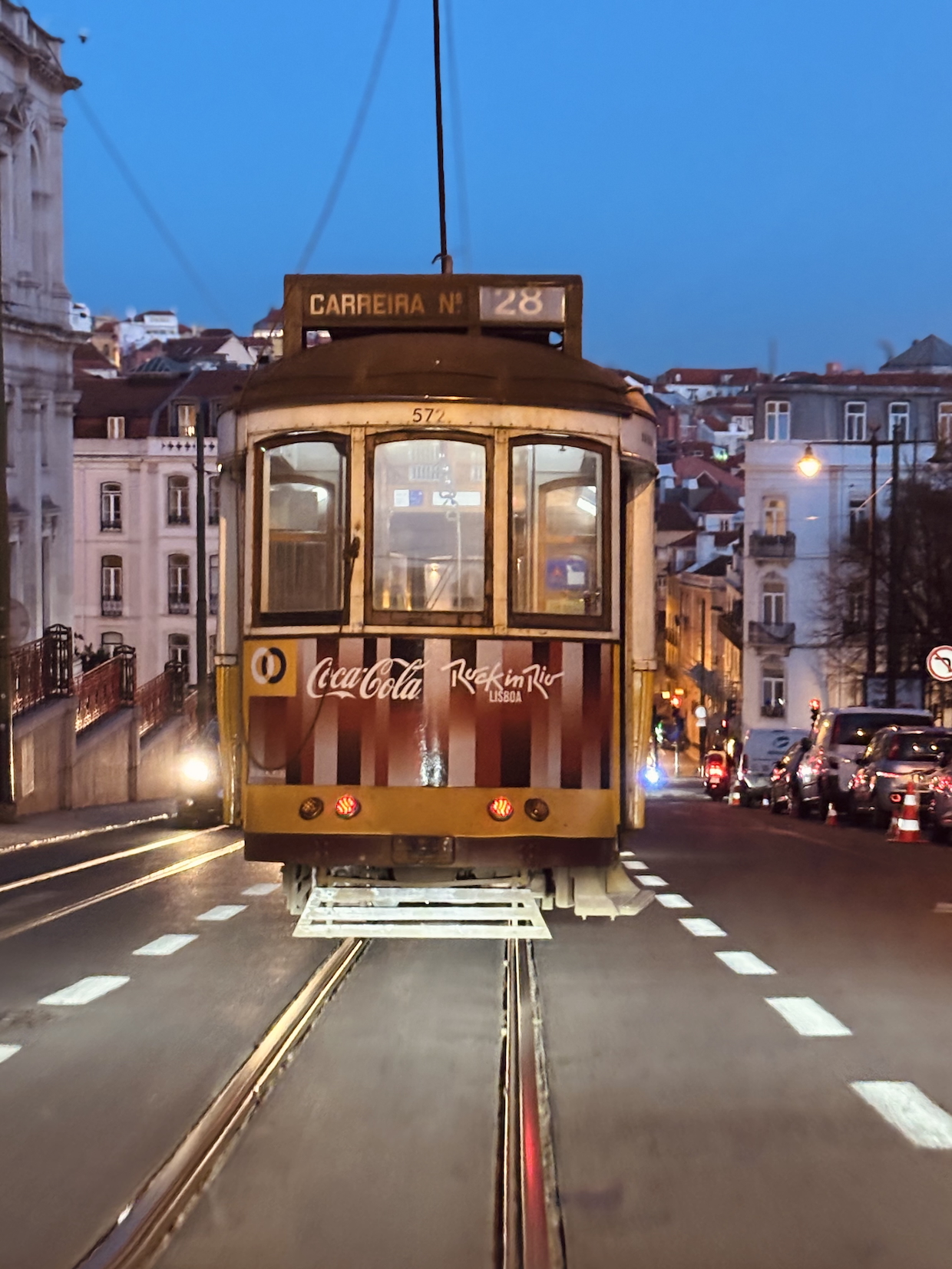 The iconic yellow Tram 28 driving through the illuminated streets of Lisbon at night.