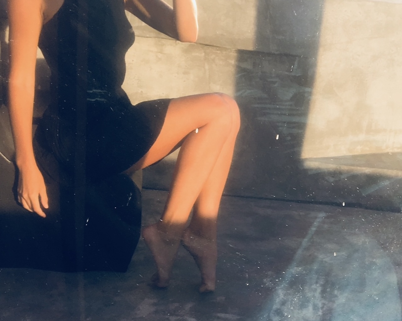 Woman in a black dress sitting in warm evening light before a date in Lisbon